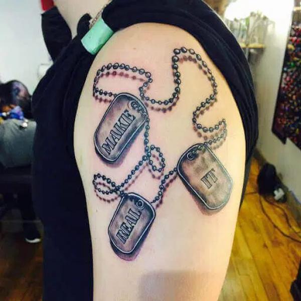 Three dog tags with rosary tattoo on upper arm