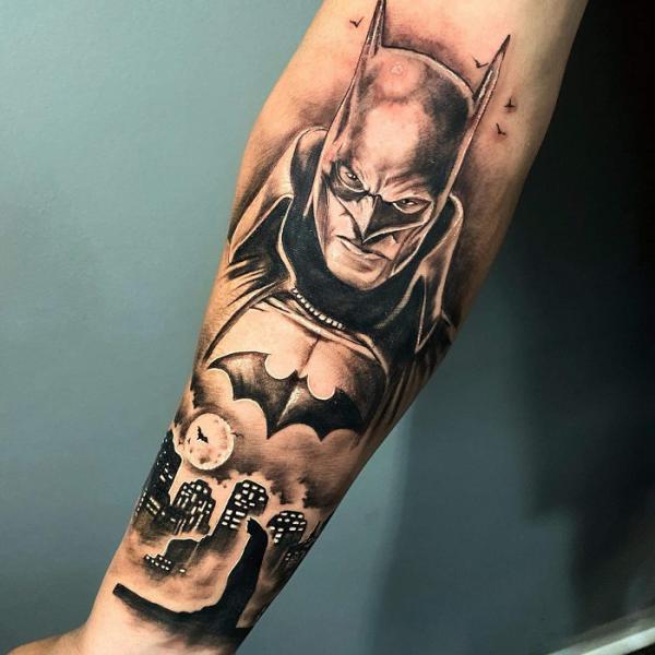 Black and white Batman and city with bat tattoo on inner forearm