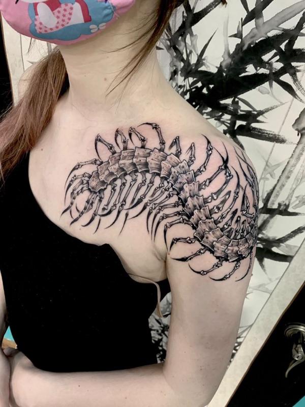 Black and white centipede tattoo on shoulder