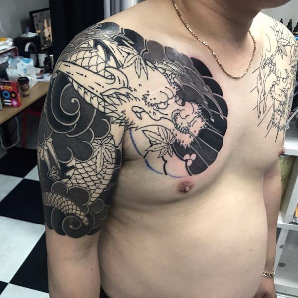 Black and white dragon chest and arm tattoo