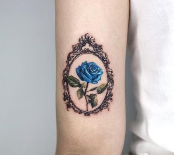 Blue rose in baroque frame tricep tattoo