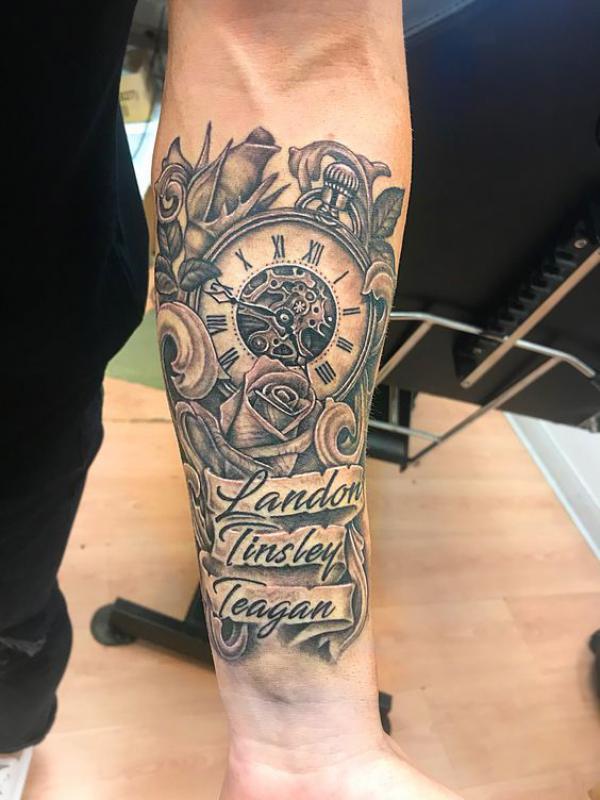 Greyscale pocket watch and roses with names tattoo forearm