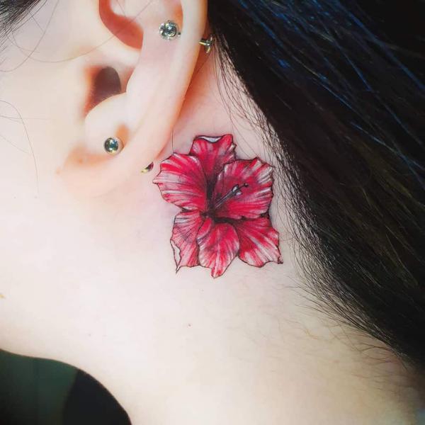 Red gladiolus tattoo behind the ear