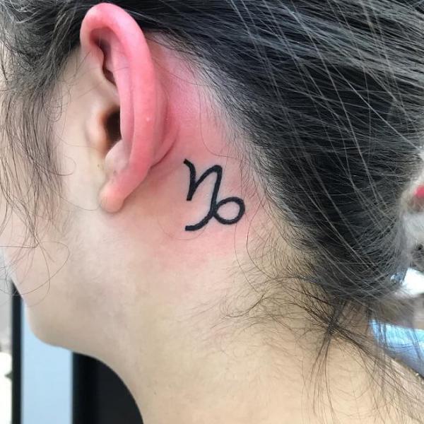 Small Capricorn sign tattoo behind the ear